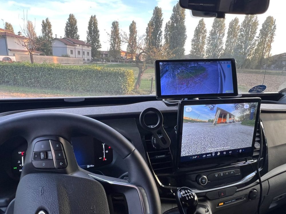 Il monitor del kit montato in plancia accanto al display del veicolo, con la vista di una telecamera